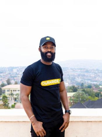 Man stands on a rooftop in a black shirt and hat. 
