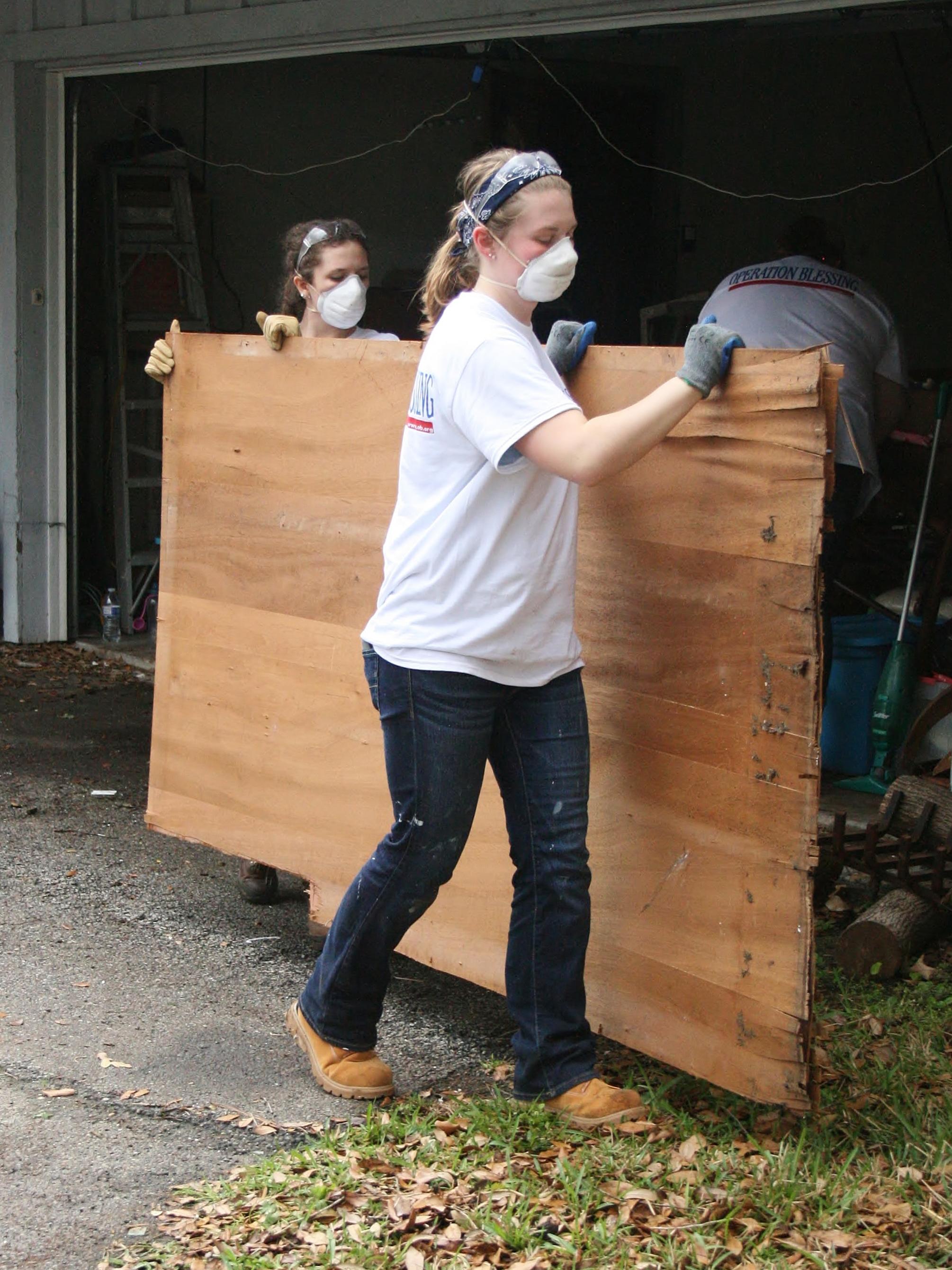 Two Penn State Behrend students remove a damaged section of wall from a home in Houston.