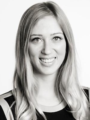 Black and white headshot of a woman smiling with long, wavy hair