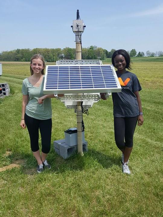 Students Worlasie Djameh and Corryn Klien stand next to the completed All-Seeing Eye.