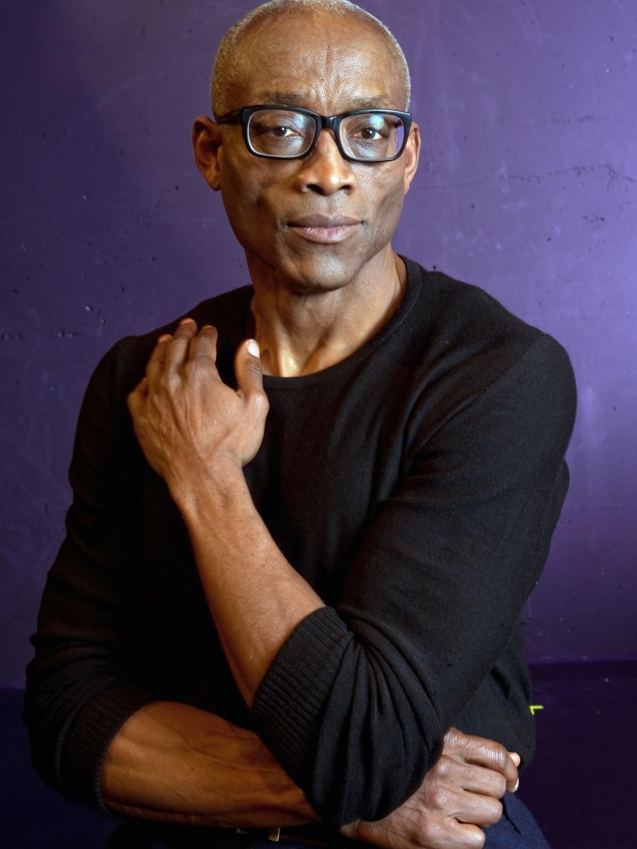 A man crosses his arms and looks at the camera.