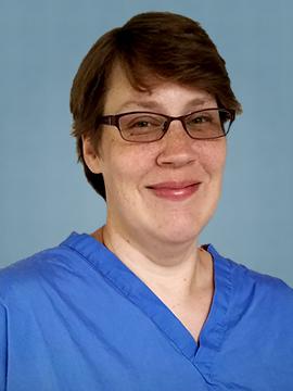 Alexandra Black poses for a photo wearing glasses and surgical scrubs.