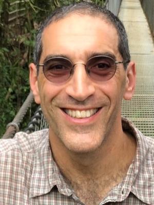 Man in sunglasses smiles for a close up photo.
