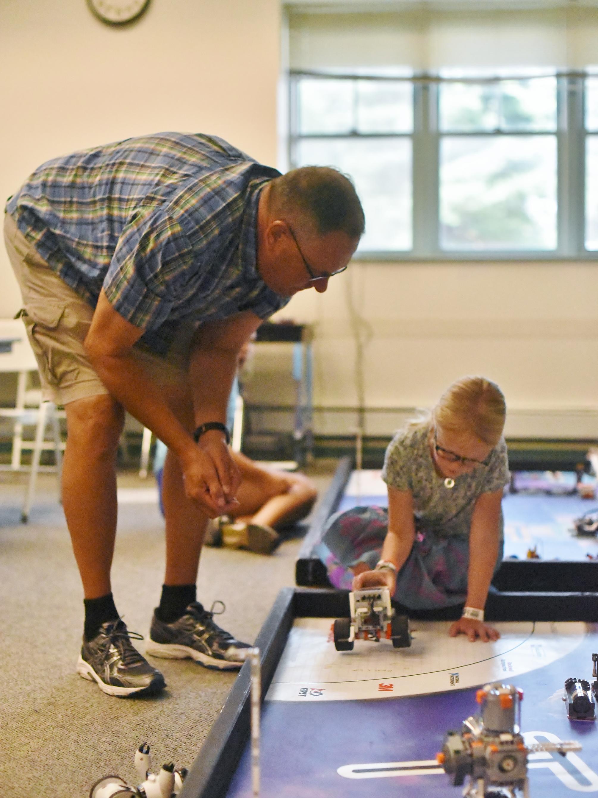 A College for Kids instructor works with a young girl in a Penn State Behrend robotics lab.