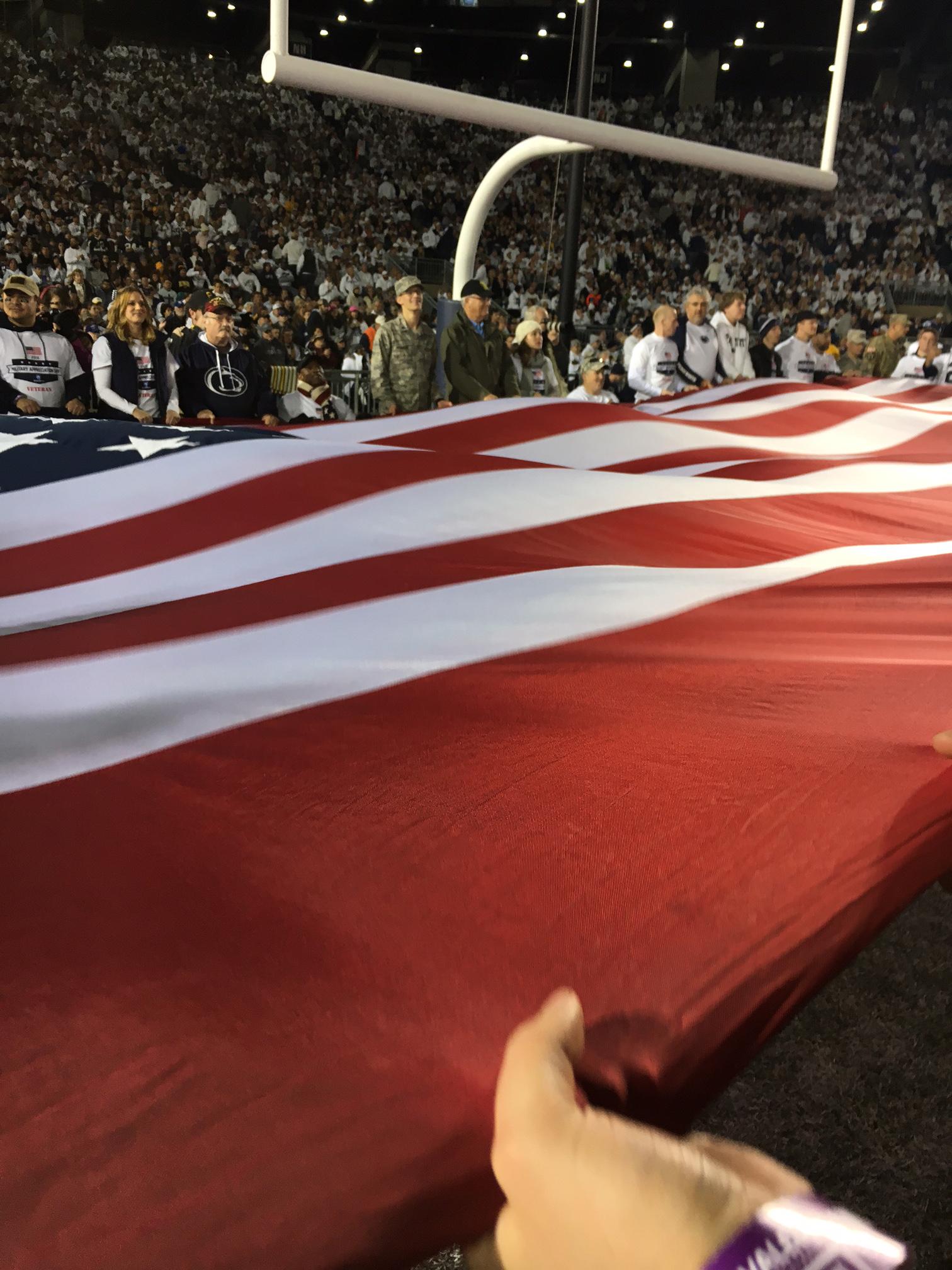 Student holding American flag across Beaver Stadium's end zone