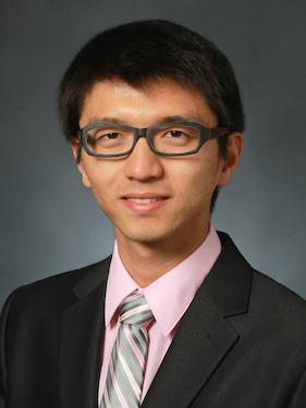 A head and shoulders shot of a man wearing a suit and glasses.