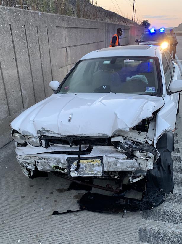 A white car, totaled, by the side of a highway