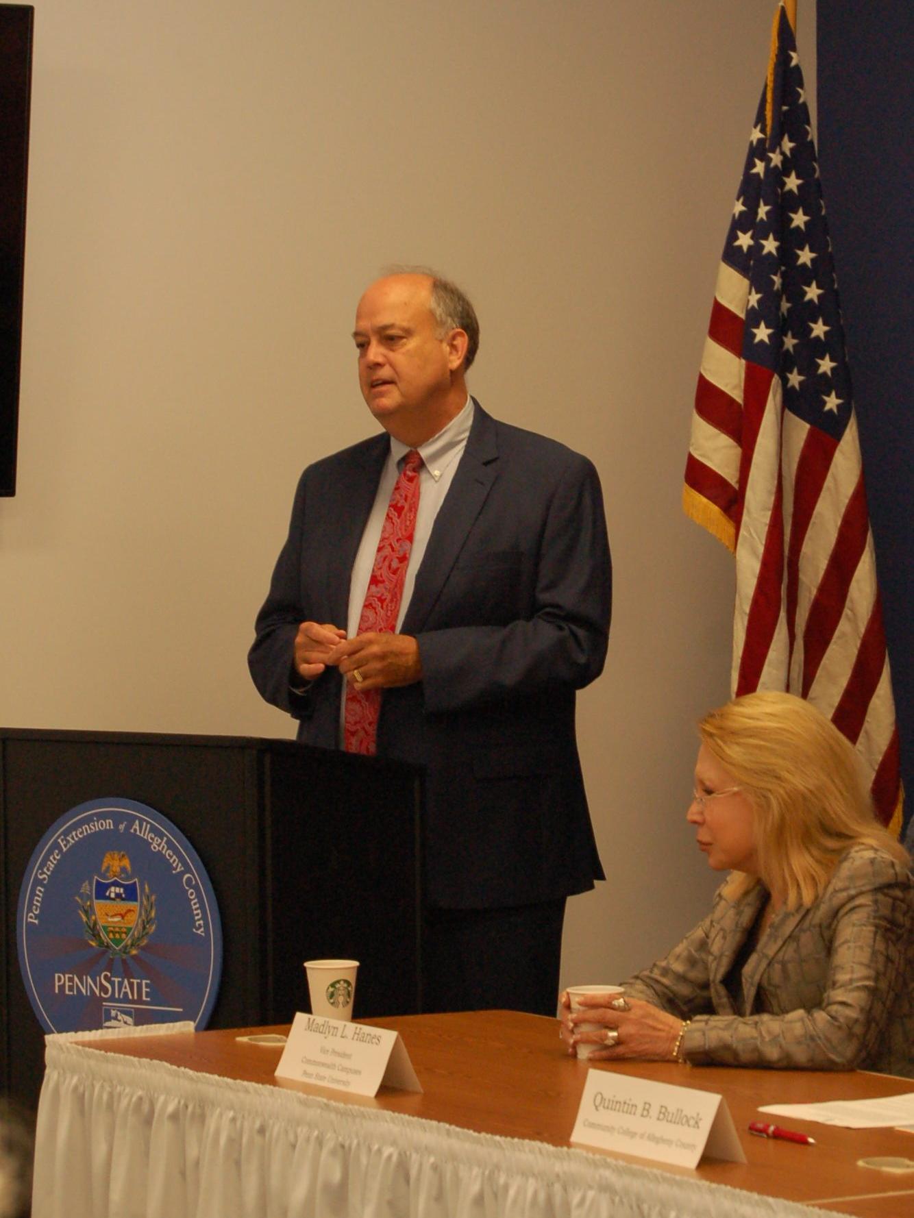 Man standing at podium near flag