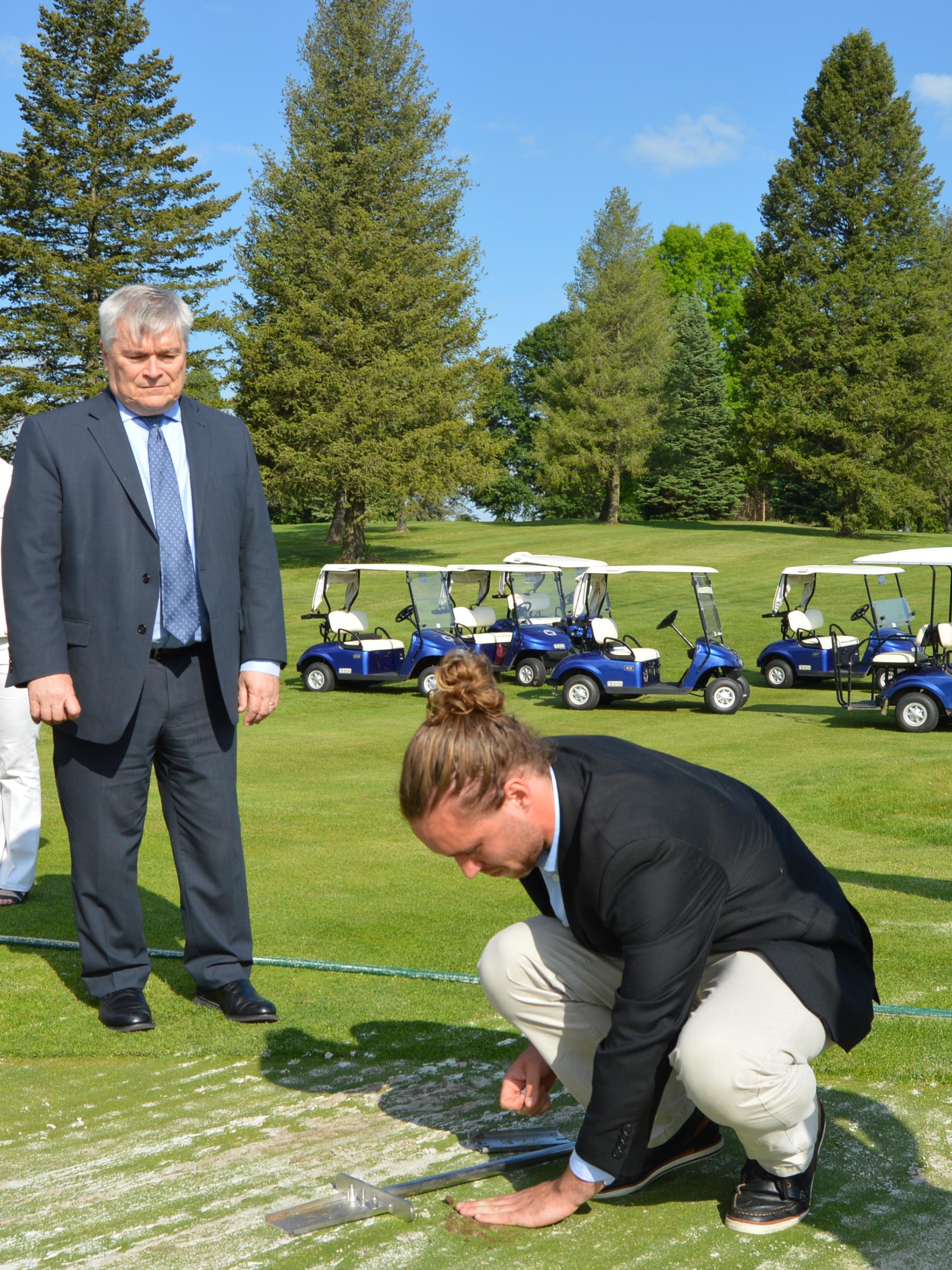Hunter Swisher demonstrates for President Eric Barron how Rhizosorb causes plant roots to grow longer