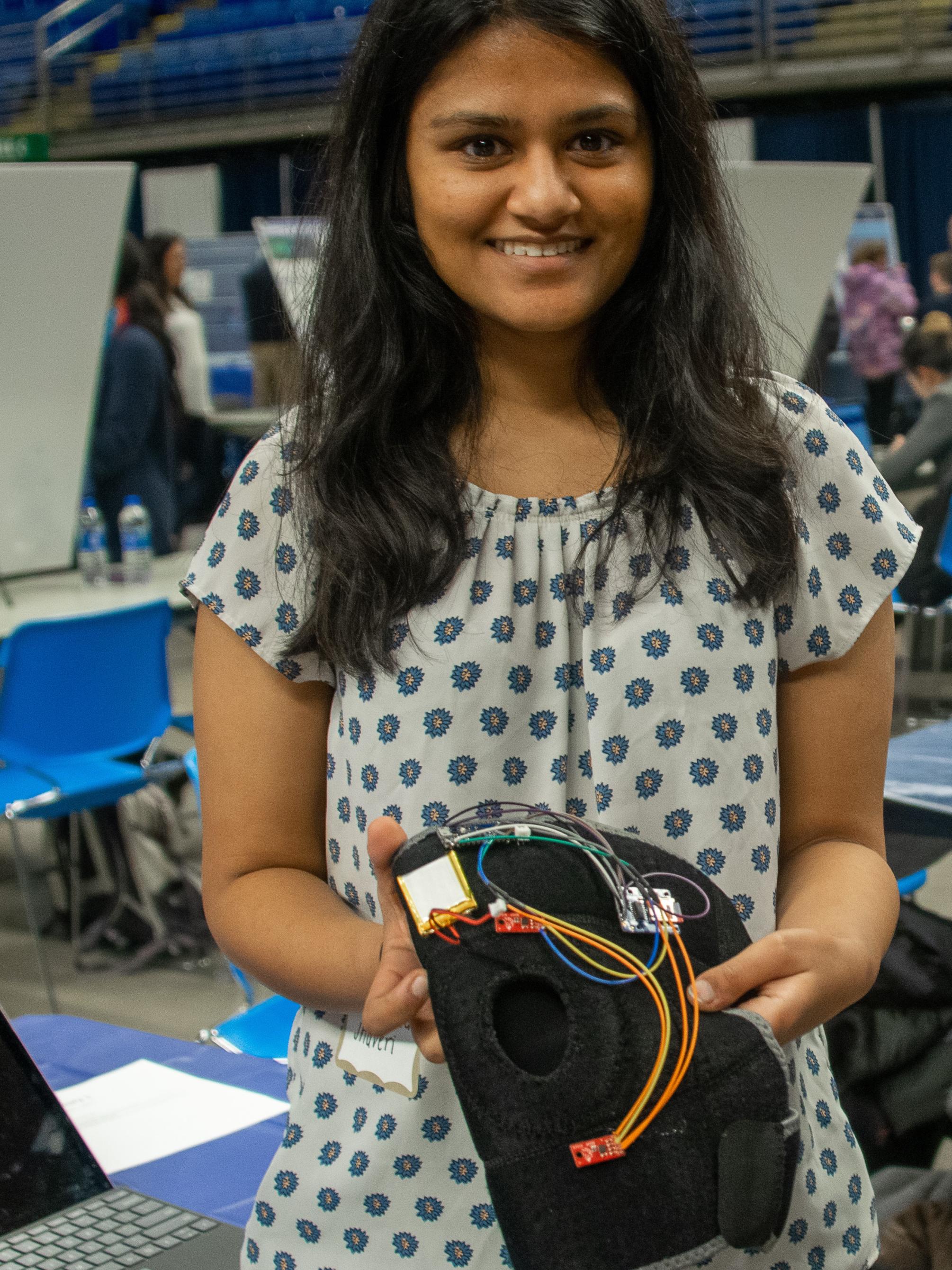 female student displays knee brace device for project