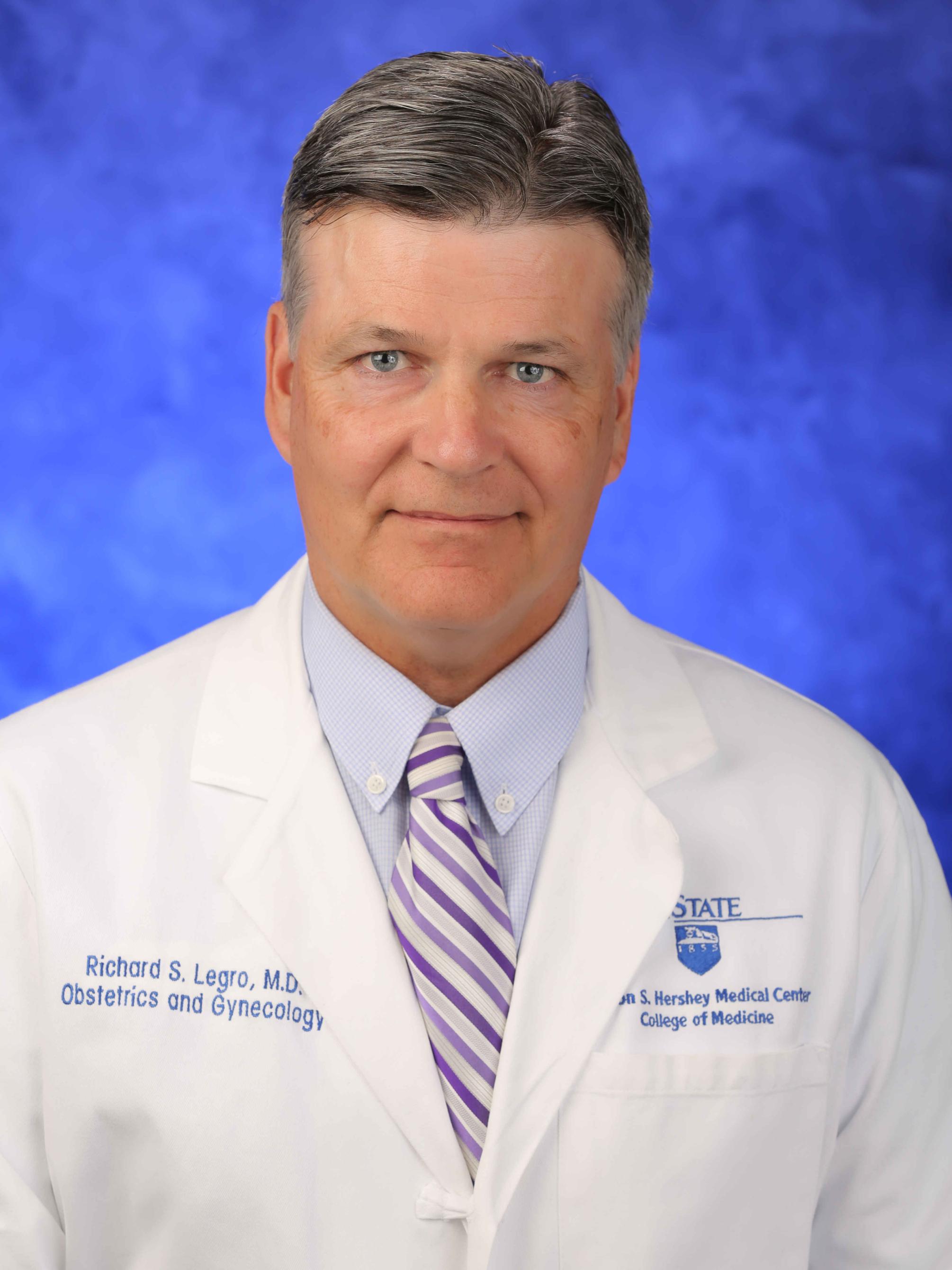 Dr. Richard Legro poses for a professional headshot photo, wearing a tie and a white physician's coat.
