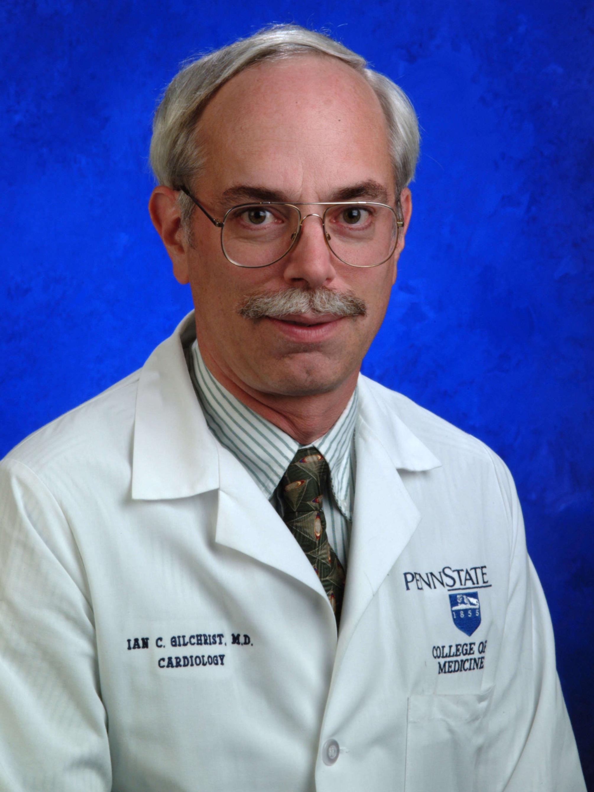 Dr. Ian Gilchrist poses for a professional photo, wearing a tie and medical coat.
