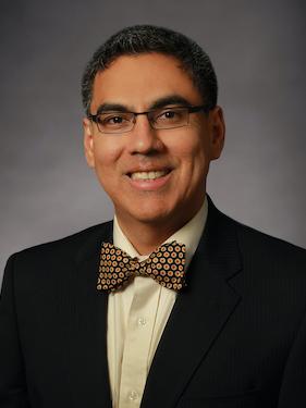 A head and shoulders shot of a man wearing a suit. 