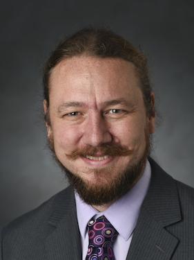 professor in business attire smiling and posing for a professional headshot photo