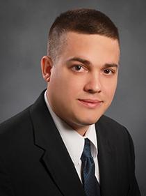 Professional headshot of dark-haired man in a suit, John Hajduk, director of PSFEI