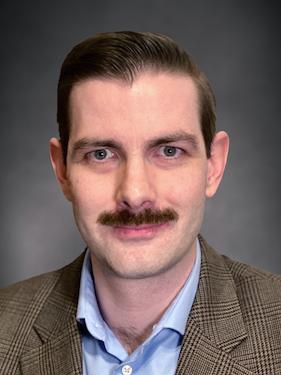 Portrait of a white man with a mustache in a tweed coat