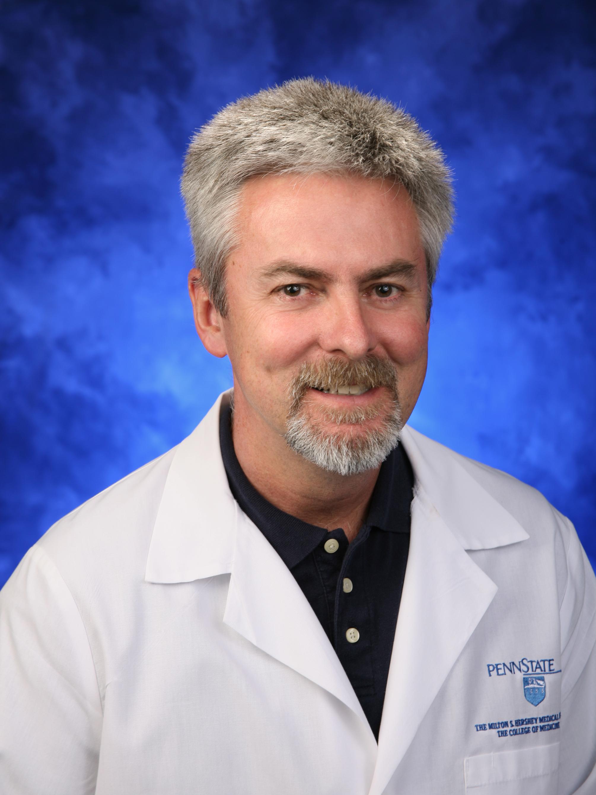 Dr. William Hennrikus is pictured wearing a white physician's coat. The background is blue.