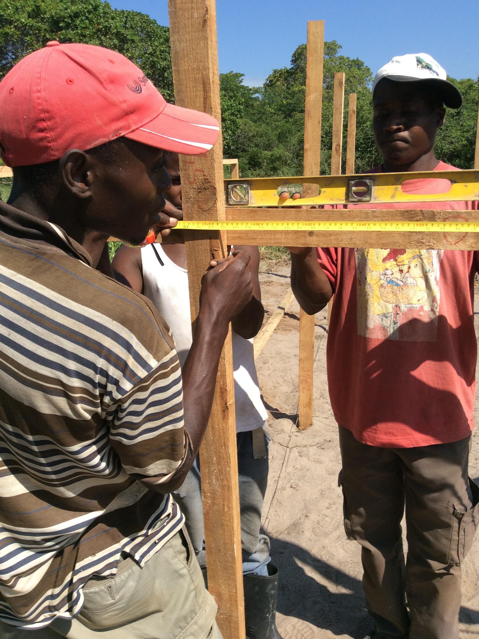 two men in Mozambique building the framework for a greenhouse.