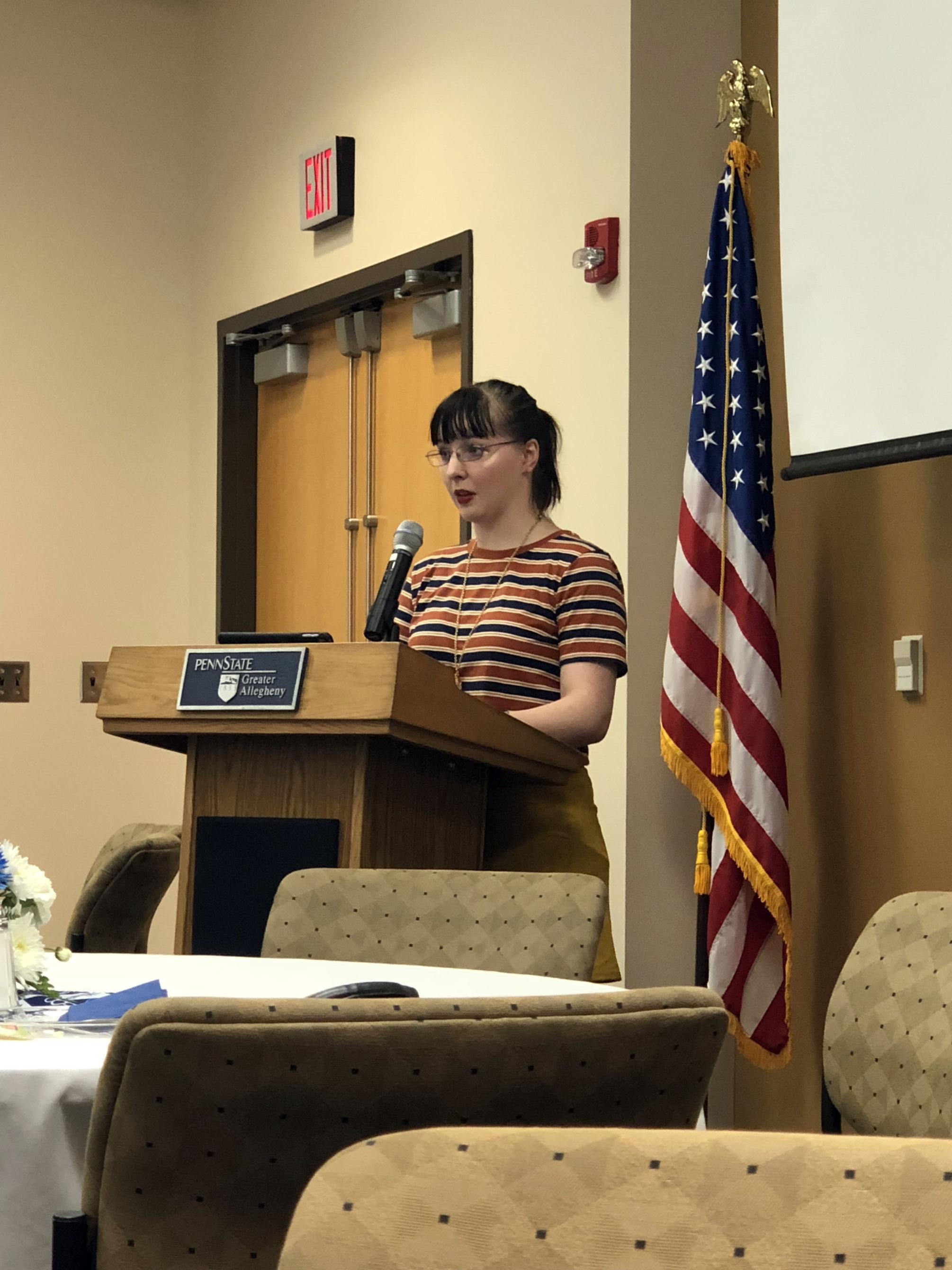 Student standing behind podium talking into microphone