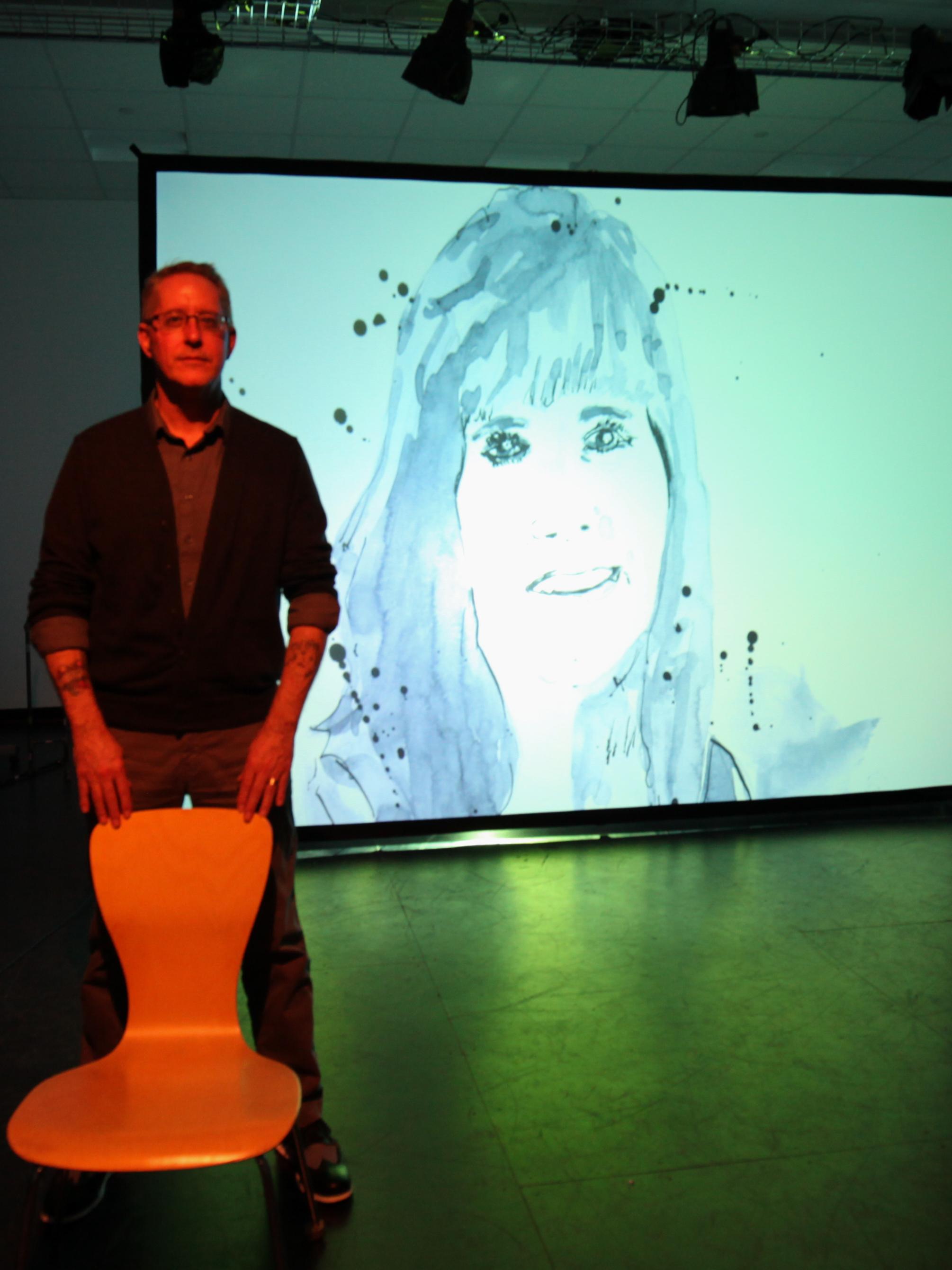 Bill Doan stands in front of a drawing of his late sister, Sam, from his graphic novel, on the screen during rehearsal for "Drifting."