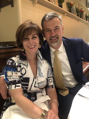 husband and wife sitting at a table, smiling and posing for a photo