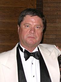 photo portrait of white man in white tuxedo, black tie, black vest, white dress shirt