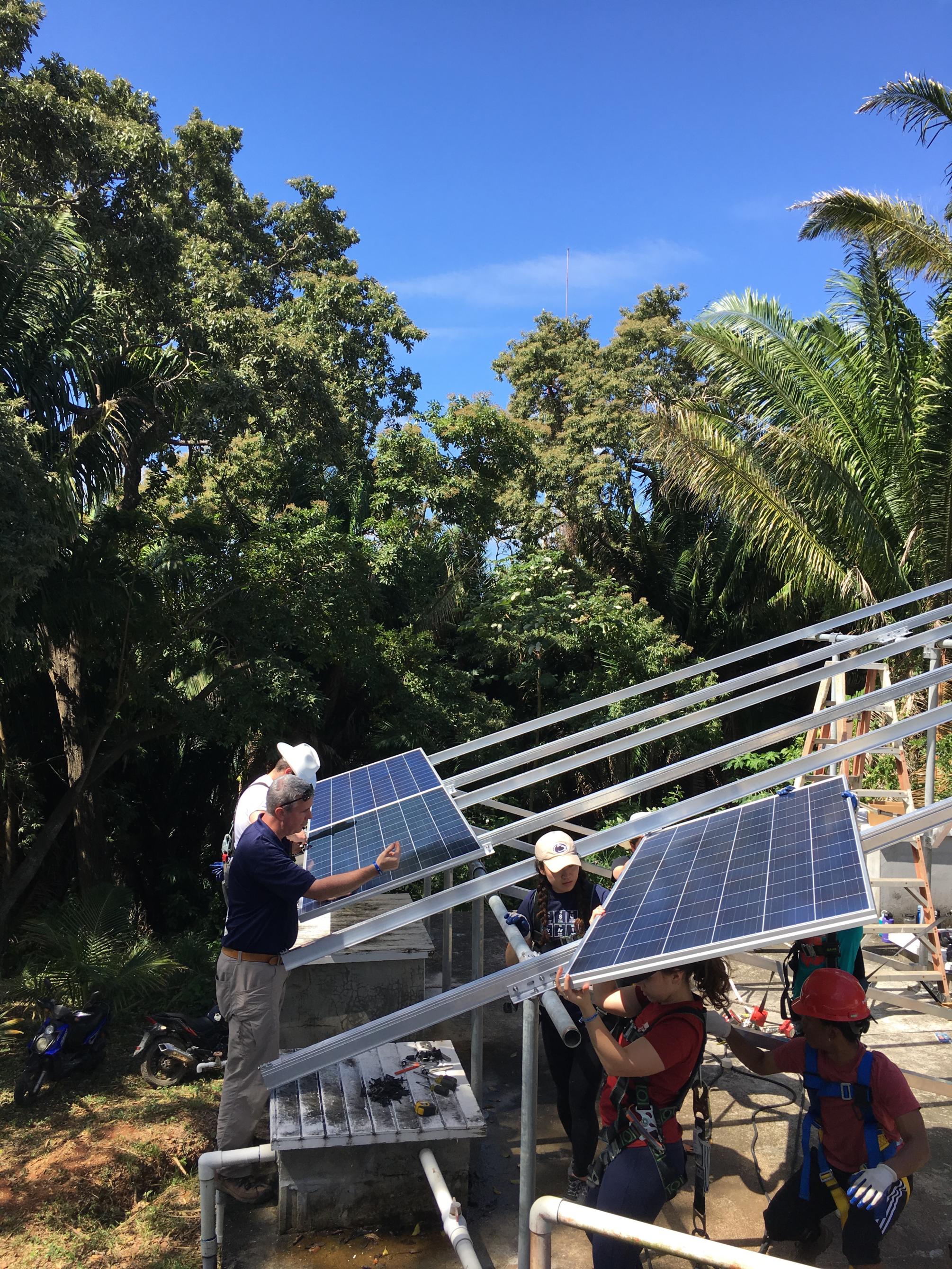 People work to install a solar panel in Roatán
