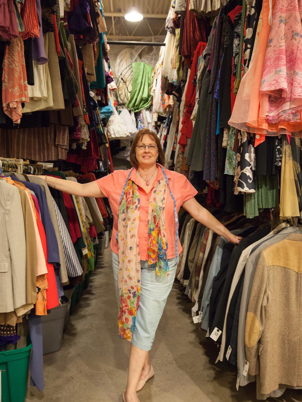 Diane Toyos standing between Costume Shop clothing racks. 