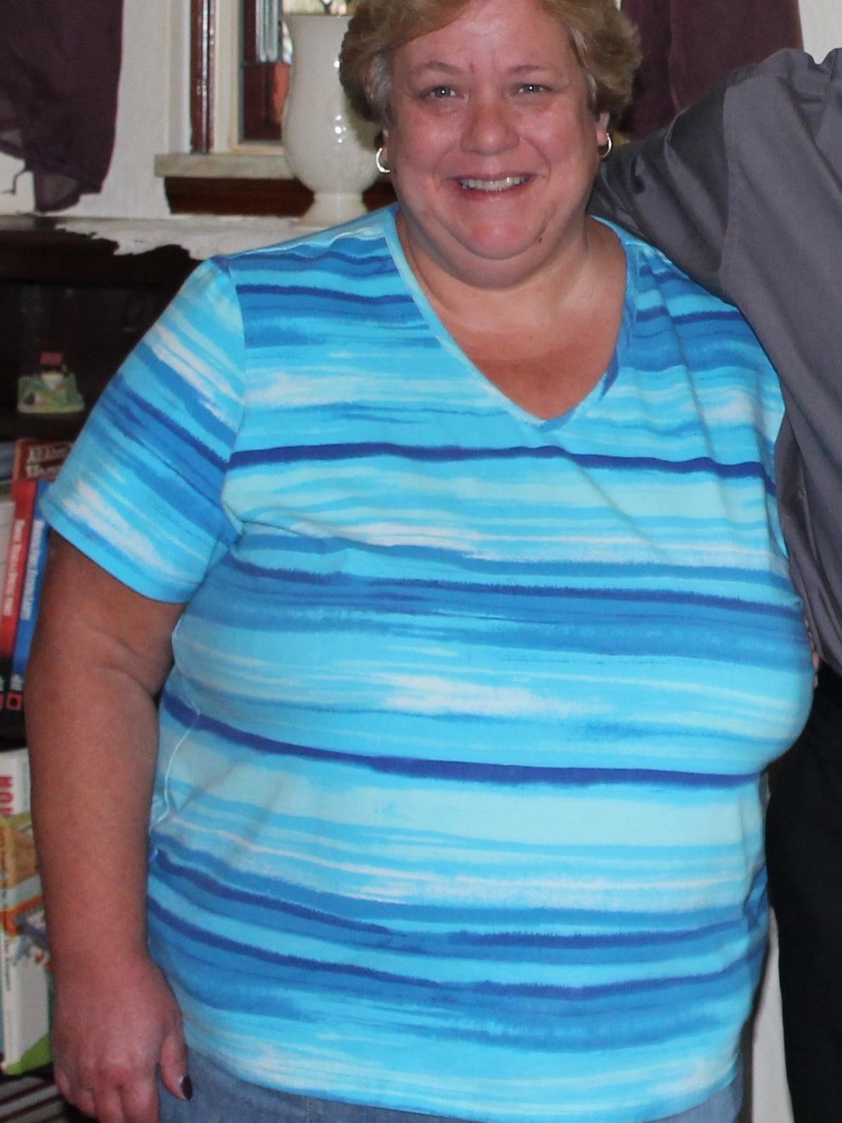 Photo of Colin's mother smiling wearing a multi colored strip shirt 