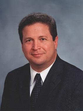 professor in business attire smiles and poses for a professional headshot photo
