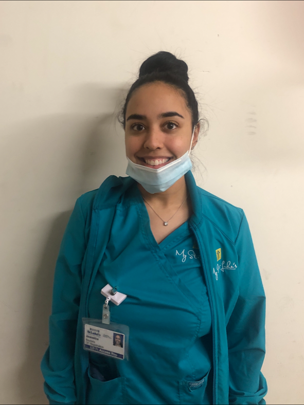 young woman wearing scrubs and with mask around her chin