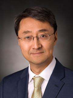 male professor in business attire smiles and poses for professional headshot