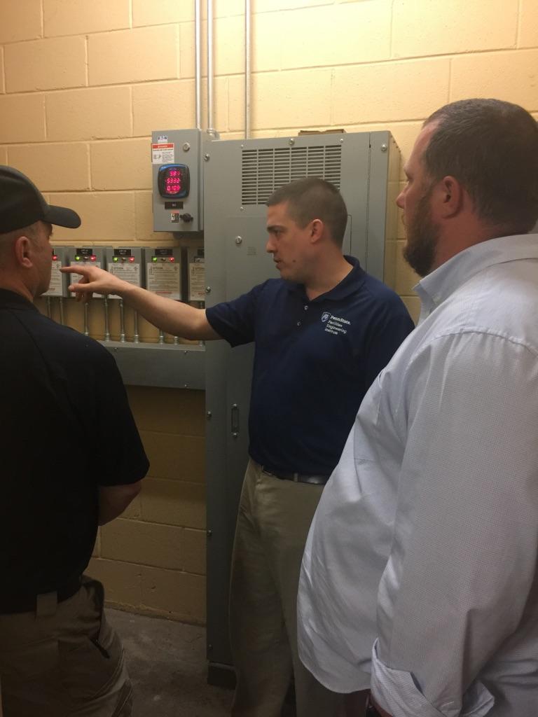 Man explaining operation of an emergency power panel to a group of students