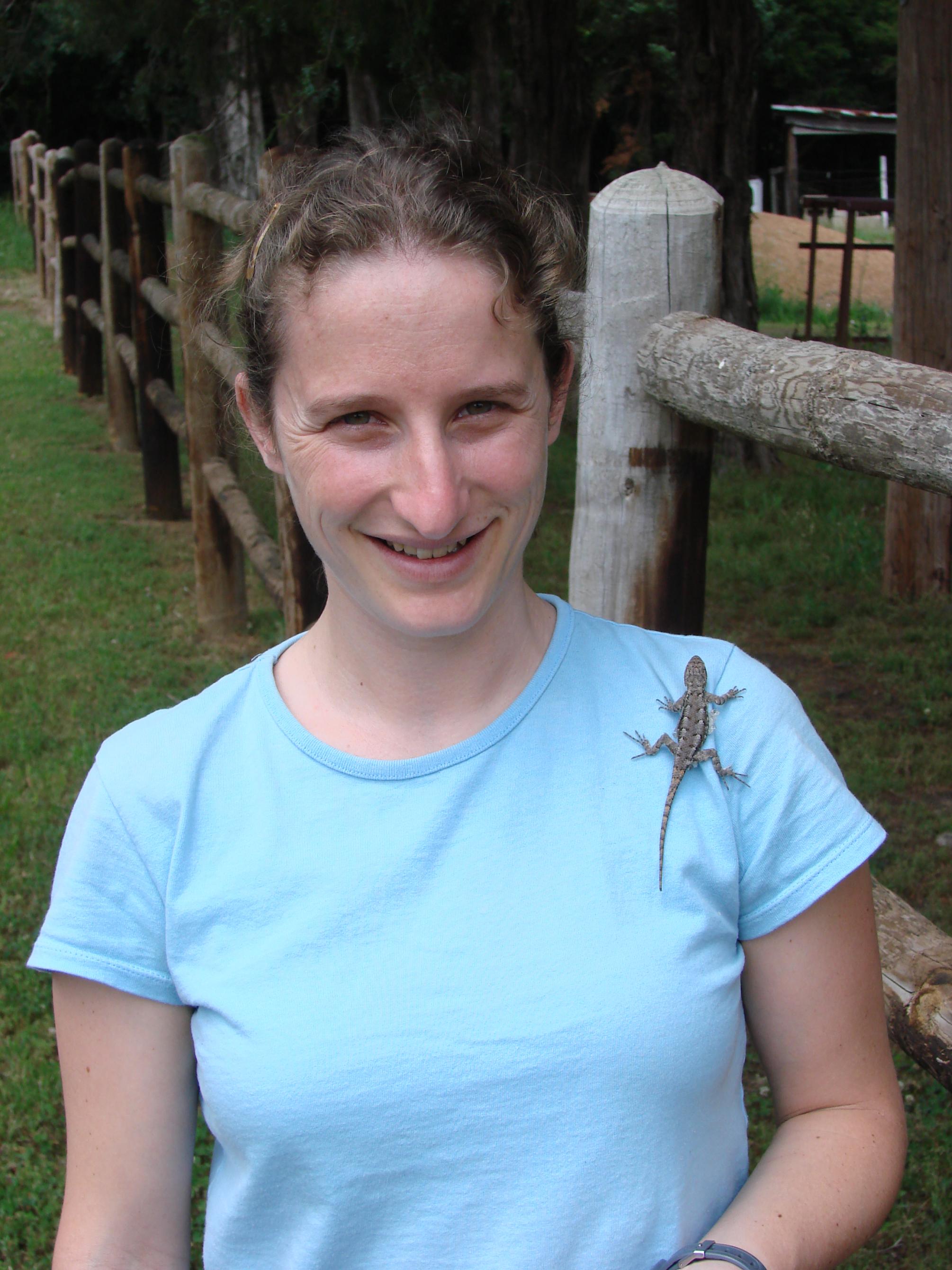 Penn State scientist Tracy Langkilde, in a blue t-shirt with a lizard climbing on her shoulder