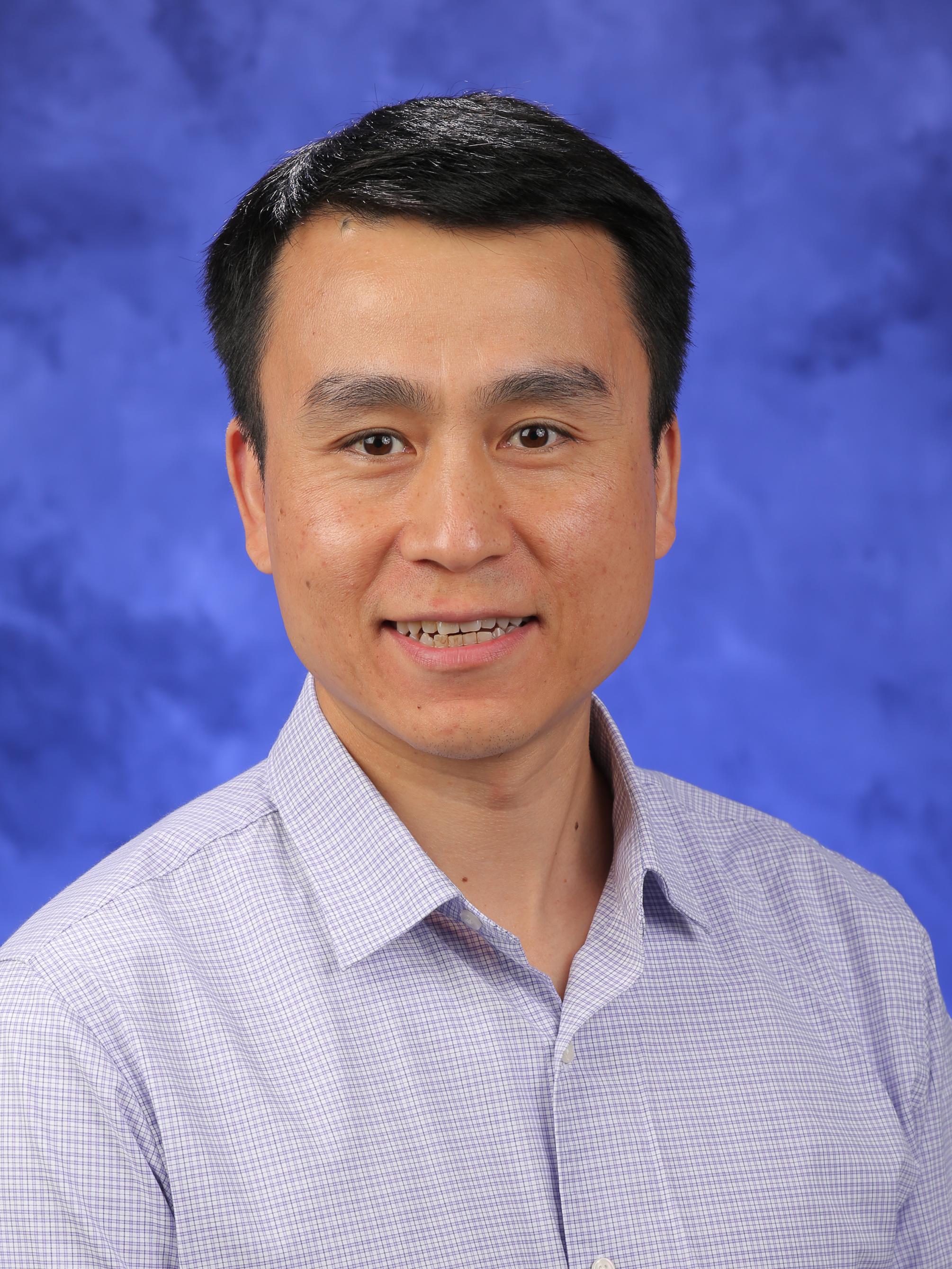 Wei Li poses for a professional headshot, wearing a button-down shirt.