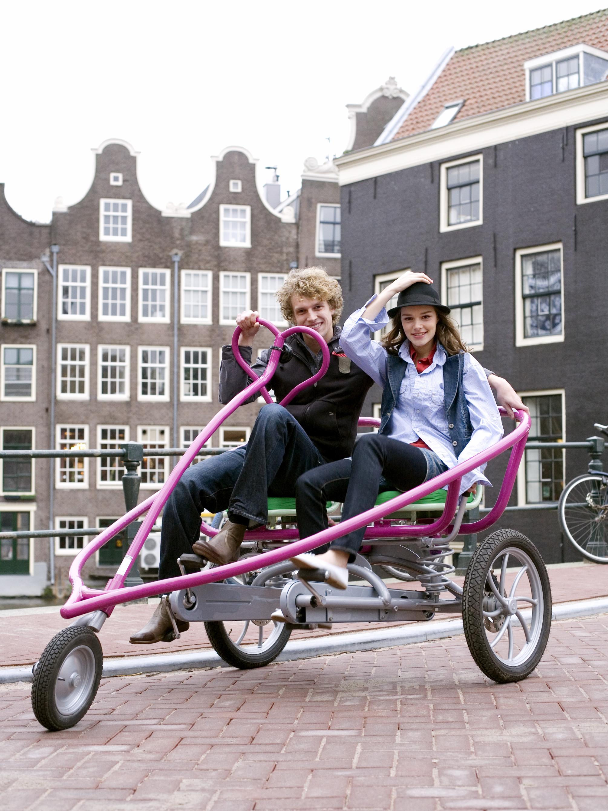 A couple demonstrates the "LoveBike" created by Eric Staller. Intended as a love-poem for his wife, this purple, heart-shaped bike seats two people and is one of only 10 ever produced.
