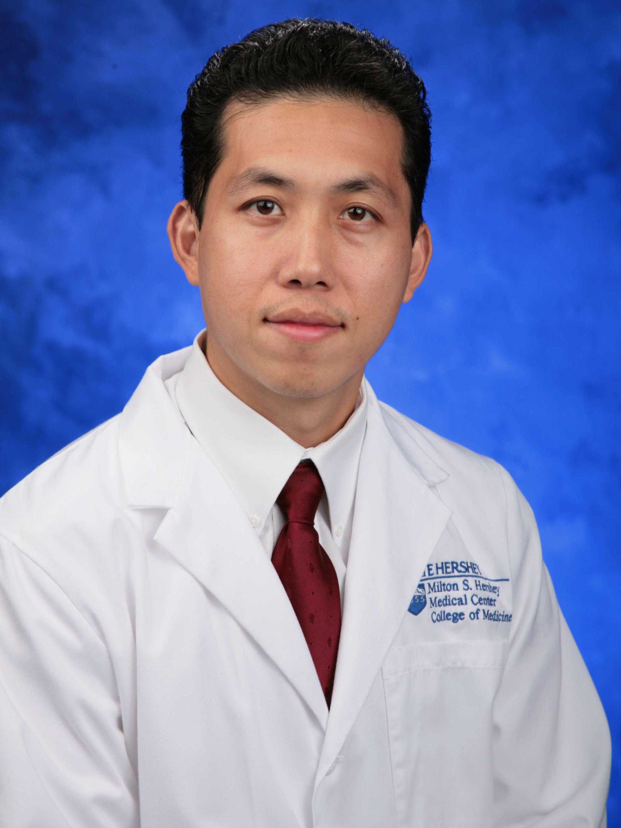 Dr. Jerome Lyn-Sue poses for a professional headshot wearing a tie and a medical coat.