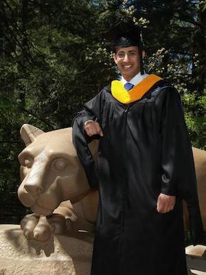 A man stands in master's robes with the Nittany Lion
