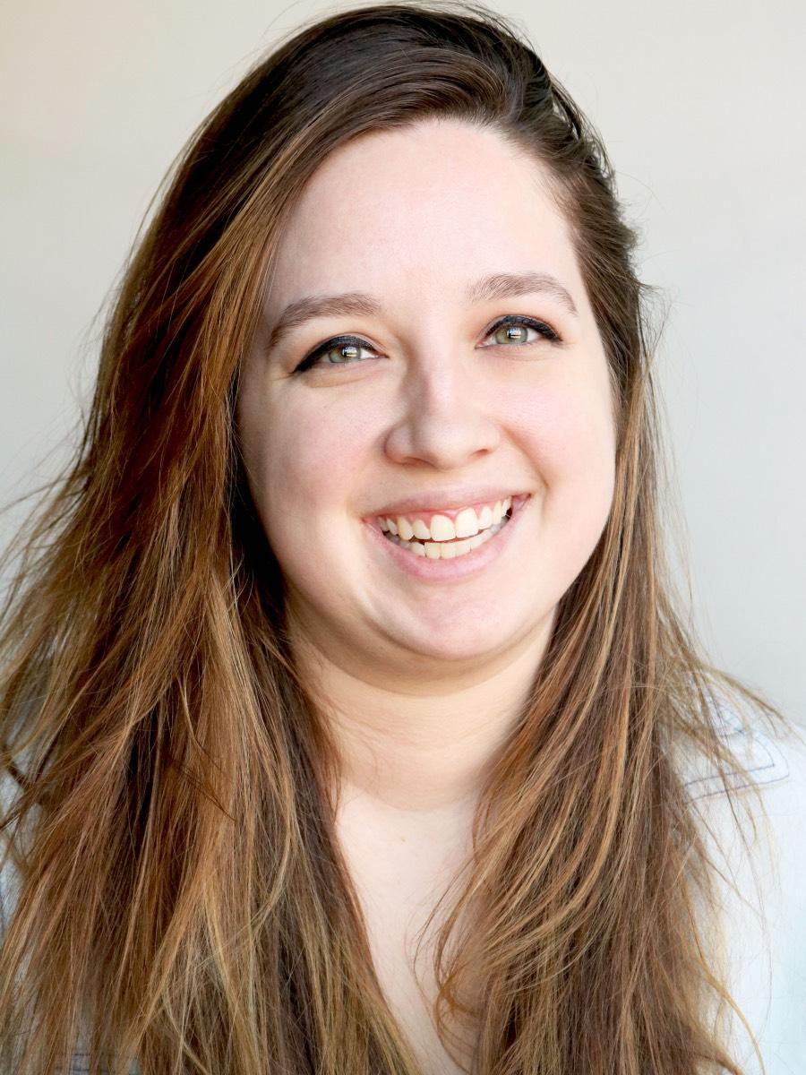 A woman shown from the shoulders up in a portrait photo smiles for the camera.