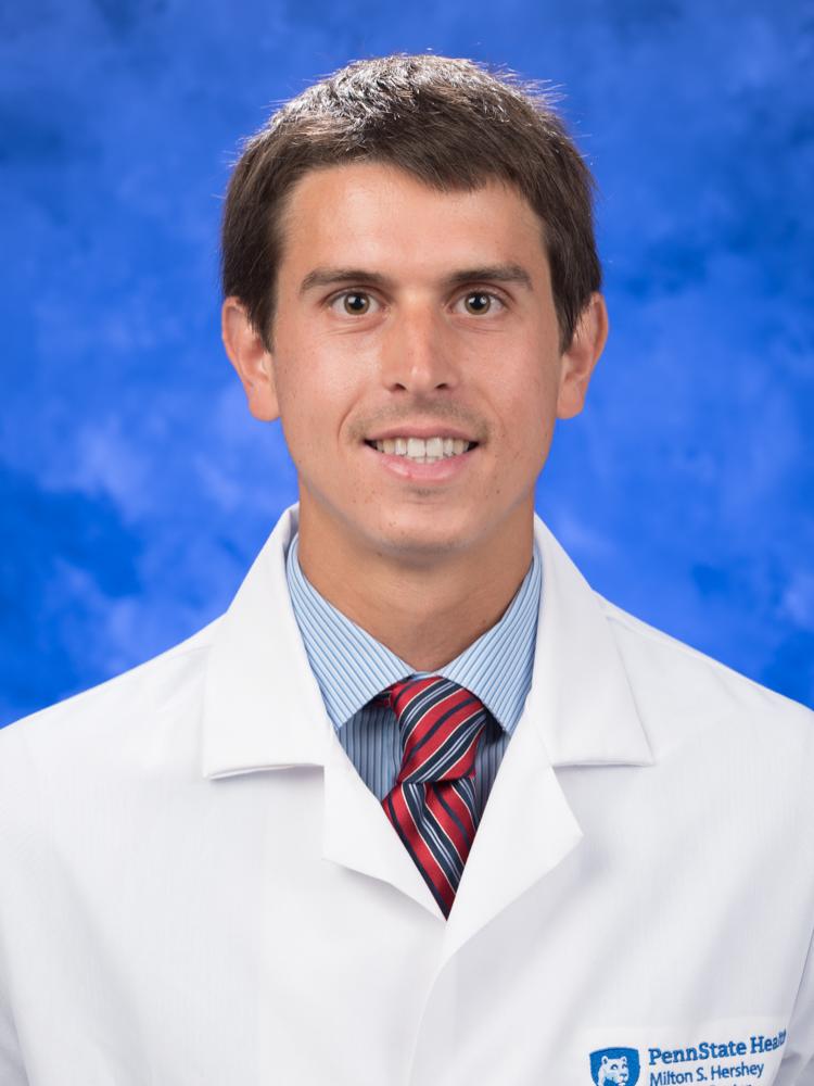 Dr. Peter Malamas poses for a headshot photo, wearing a tie and physician coat.