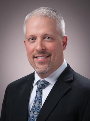  Caucasian man wearing a suit smiles.