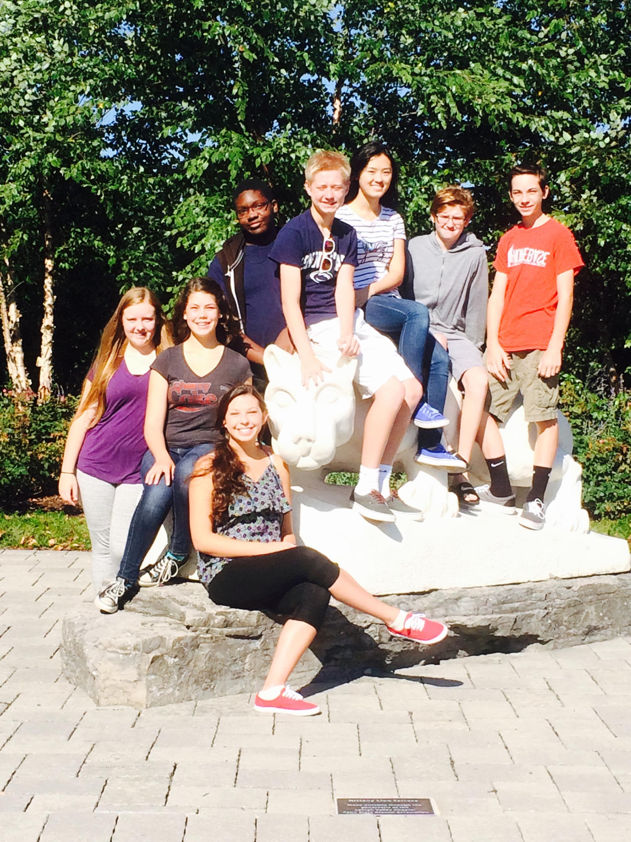 Group of eight high school students from a video camp gather with the Nittany Lion.