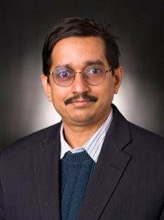 A headshot of a man in glasses and a suit jacket.
