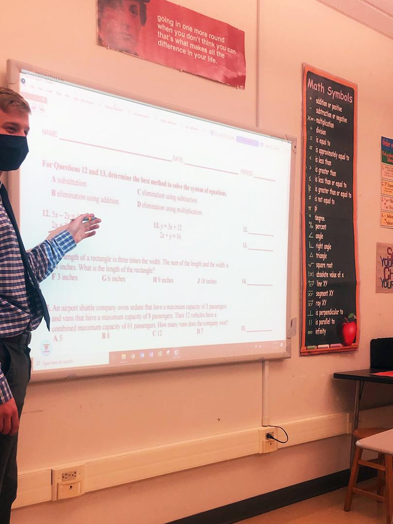 Student Teaching pointing to smart whiteboard that has math equations