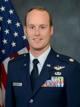 An airforce service member smiles for his headshot photo.