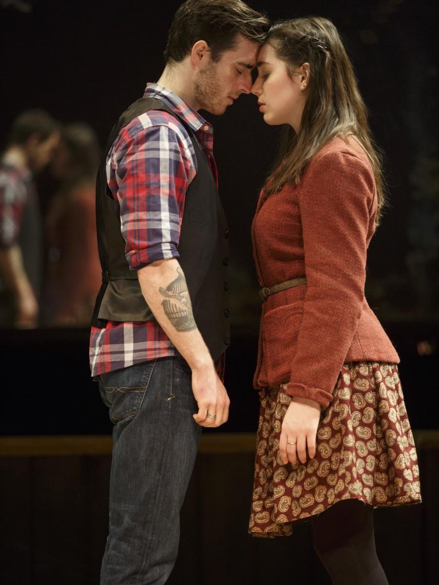 A young man and woman stand facing each other with their foreheads pressed together in a scene from “Once.” 