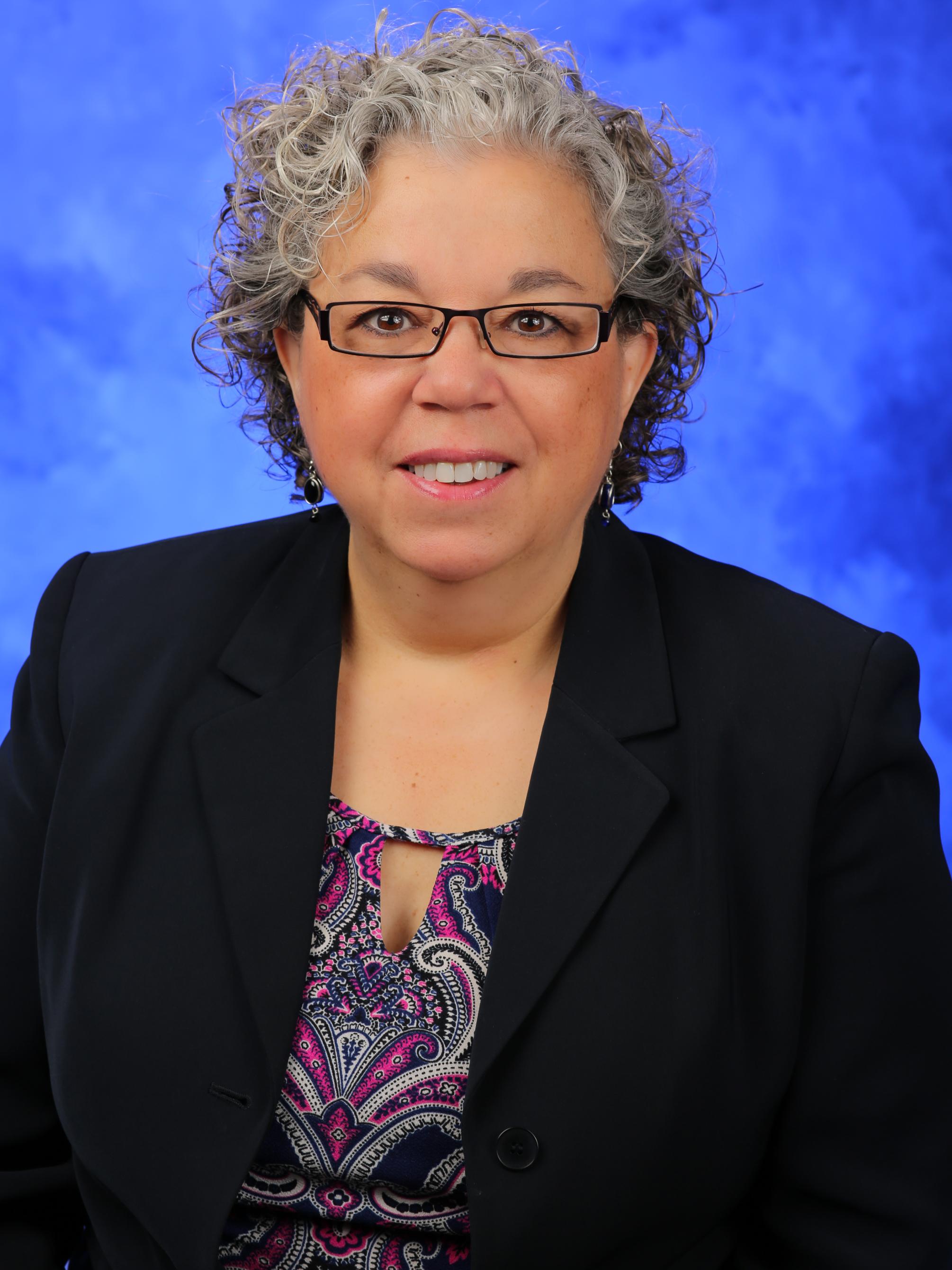 A headshot of Dr. Barbara Ostrov, against a blue background.