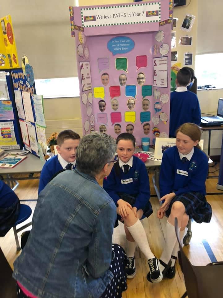 11-12 year old children in their classroom talking with Elaine Berrena