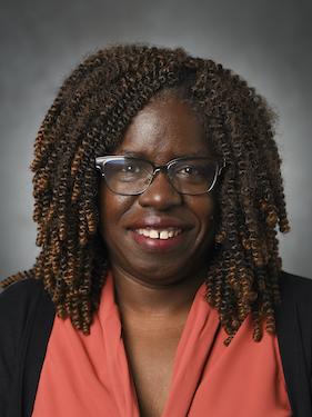 Woman in business professional attire smiles and poses for professional headshot