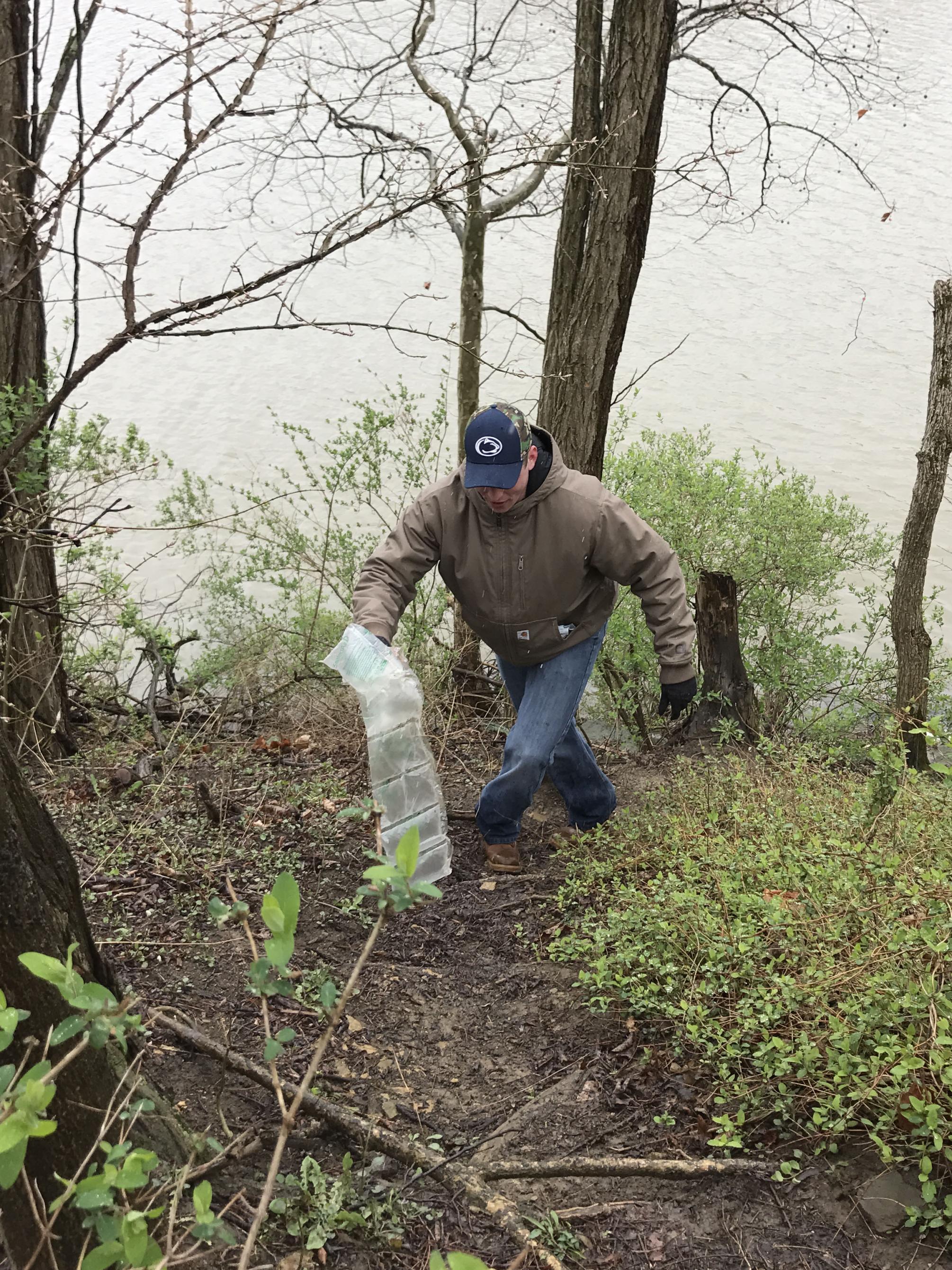 student picks up trash near lake